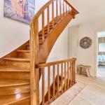 Holzgetreppe führt in Wohnbereich mit Sofa und Wandbild.