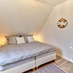 Schlafzimmer mit Doppelbett, Nachttisch und Wanddekoration.