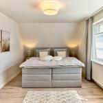 Schlafzimmer mit Bett, Fenster und Wandbildern.