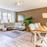 Wohn- und Essbereich mit Holzwand, Sofa und Holztisch.