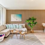 Wohnzimmer mit Sofa, Holzwand, Pflanze und Sitzgelegenheiten.