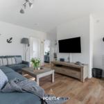 Wohnzimmer mit Sofa, Fernseher und Kaminofen.