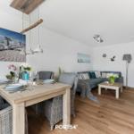 Essbereich mit Tisch und Stühlen. Wohnbereich mit Sofa und Couchtisch.