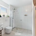 Badezimmer mit Dusche, Waschbecken und Toilette. Sauna im Anschluss.
