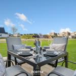 Garten-Terrasse mit Tisch und Stühlen, Blick auf Gras und Häuser