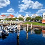 Bootshafen mit Booten und Blick auf städtische Gebäude am Wasser.