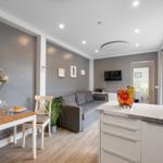 Wohn- und Essbereich mit Sofa, Tisch und Kücheninsel.