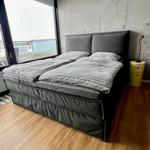 Schlafzimmer mit großem Bett, Holzboden und großer Fensterfront.