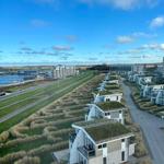 Modernes Ferienhaus mit Grasdach und Balkon. Blick auf Wasser und Strand.