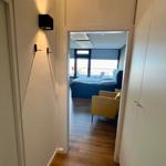 Flur mit Holzboden führt in ein Schlafzimmer mit Bett und Sessel.