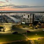 Marina mit Booten und modernem Gebäude bei Sonnenuntergang.