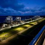 Nachtansicht von modernen Gebäuden und beleuchteten Straßen am Wasser.