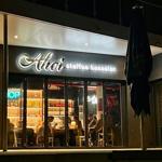 Außenansicht von Ahoi steffen henssler mit beleuchteter Fassade und Sitzgelegenheiten im Inneren.