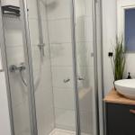 Duschkabine mit Glaswänden, Waschtisch und Pflanze