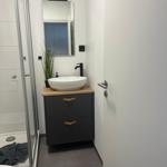 Badezimmer mit Dusche, Waschbecken und Spiegel