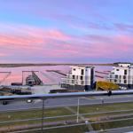 Blick auf moderne Gebäude und Hafen bei rosa Sonnenuntergang.