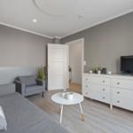 Wohnzimmer mit Sofa, Sessel, Couchtisch und TV-Schrank.