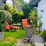 Garten mit orangefarbenen Sitzgelegenheiten und Pflanzen in Körben.