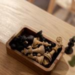 Schachfiguren in einem Holzkasten auf einem Holztisch