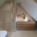 Schlafzimmer mit Kleiderschrank, Schreibtisch und Holzkommode unter Dachschrägen.