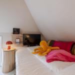 Schlafzimmer mit Bett, Fernseher und Blick auf Außenbereich.