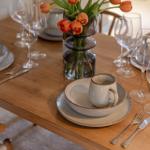 Holztisch mit Tischdekoration und orangefarbenen Tulpen.