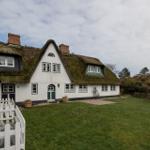 Traditionelles Haus mit Strohdach und weißer Fassade im Garten