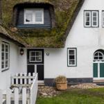 Haus mit grünem Dach und weißen Wänden, zwei Eingänge und Fenster mit grünen Rahmen.