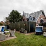 Hinterhof mit Gartenmöbeln, Strandkörben und Steinfiguren vor einem Haus.