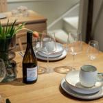 Gedeckter Tisch mit Weinflasche, Gläsern und Tulpen im Vase.