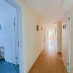 Flur mit Holzboden und Türen zu Räumen. An der Wand hängen Bilder.