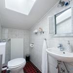 Badezimmer mit Toilette, Waschbecken und Spiegel. Rote Fliesenboden und weiße Wandfliesen.