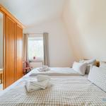 Zimmer mit Doppelbett, Kleiderschrank und Fenster mit Blick auf Bäume.