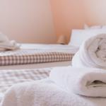 Zwei Betten mit karierten Bettwäsche und gefalteten Handtüchern.