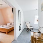 Schlafzimmer mit Dachschrägen und Holzbett. Flur mit Schaukelstuhl und Spiegel.