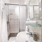 Badezimmer mit Dusche, Waschbecken und Spiegel. Handtücher und Seife sind vorhanden.