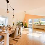 Essbereich mit Tisch, Stühlen und Fenster. Wohnbereich mit Balkontür und Pflanzen.