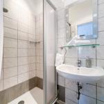 Badezimmer mit Dusche, Waschbecken und Spiegel