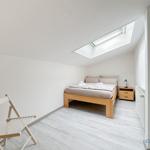 Schlafzimmer mit Dachschrägen, Bett, Nachttisch und Sitzgelegenheit.