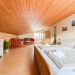 Schlafzimmer mit Doppelbett, Wohnbereich und Holzdecke.