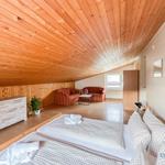 Schlafzimmer mit Doppelbett, Couch und Holzdecke.