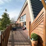Holzterrasse mit Pflanzen und Blick auf Hauswand.