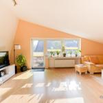 Wohnzimmer mit Sofa, Fernseher und Balkonzugang.