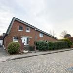 Ein zweistöckiges Haus mit rotem Backsteinfassade und Vorgarten. 