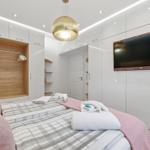 Schlafzimmer mit Bett, Kleiderschrank und Fernseher an der Wand.