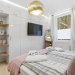 Schlafzimmer mit Bett, TV und Fenster zum Wald