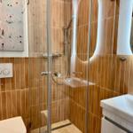 Duschbereich mit Glaswand, Waschbecken und Wandkunst