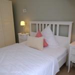Schlafzimmer mit weißem Bett, Nachttischen und Kleiderschrank.