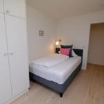 Schlafzimmer mit Bett, Kleiderschrank und Holzboden.