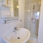 Badezimmer mit Waschbecken, Spiegel und Dusche.